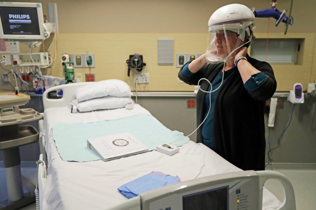 U.S. Health Care System : A nurse demonstrates how she wears a respirator helmet with a face shield intended to prevent infection. 