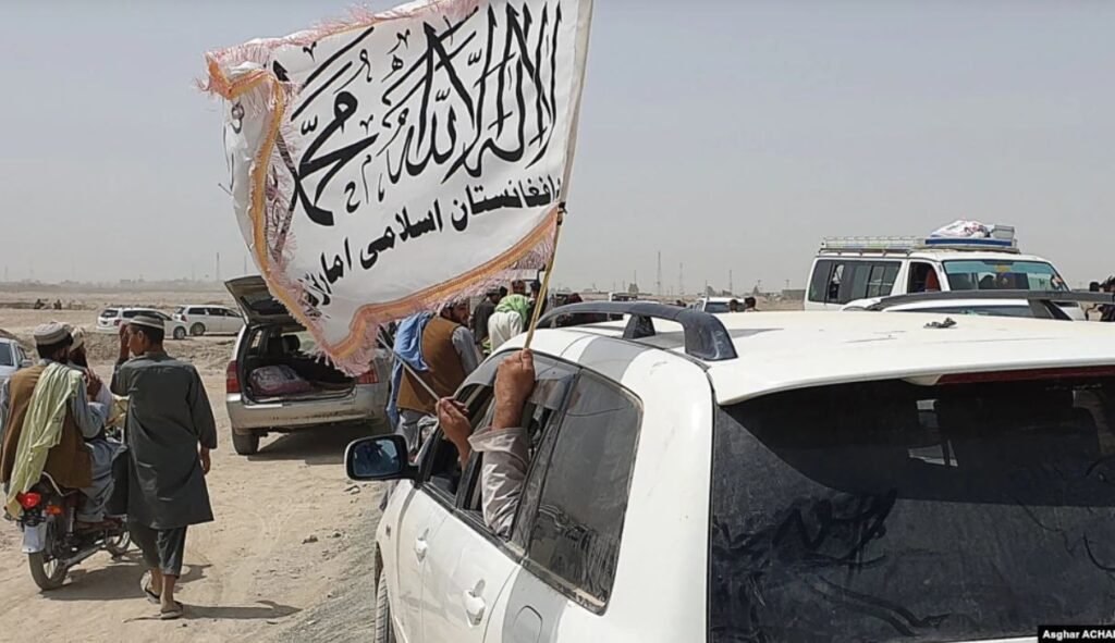 If you Think Afghanistan is Fighting War with Taliban, Think Twice - Afghanistan is Fighting War Against Pakistani Punjab - People wave a Taliban flag as they drive through the Pakistan occupied border town of Chaman on July 14, after the Taliban claimed it had captured the Afghan side of the border crossing at Spin Boldak. | NewsComWorld.com